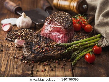 Slice Of Raw Beef Topside Joint With Salt And Pepper On Wooden Chopping Board With Tomatoes Garlic A