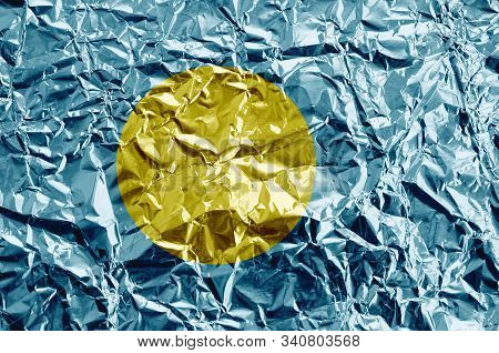 Palau Flag Depicted In Paint Colors On Shiny Crumpled Aluminium Foil Closeup. Textured Banner On Rou