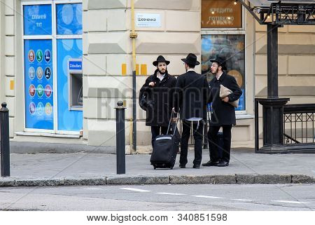 3 Jewish Boys, Hasidic Jews, In Black Clothes And Hats With Suitcases And Luggage Stand On The Stree