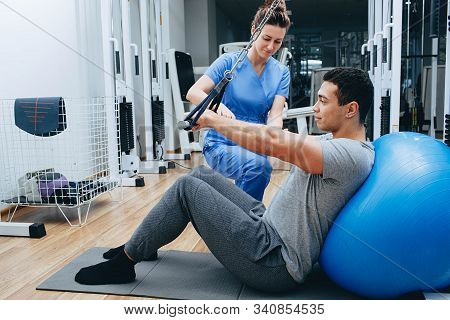 Kinesiologist Helps A Mixed Race Man Doing Exercises To Strengthen His Back Muscles. Treatment Of Ba