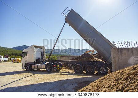 Dump Truck Unloads From The Body Of The Sand At The Concrete Plant. The Dump Truck Lifts The Body An