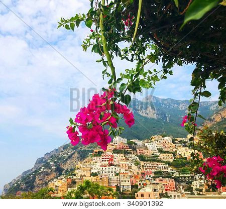 Beautiful Positano View On Mountains With Colorful Houses Framed With Blooming Flowers Photo.