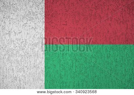 Madagascar Flag Depicted In Bright Paint Colors On Old Relief Plastering Wall. Textured Banner On Ro