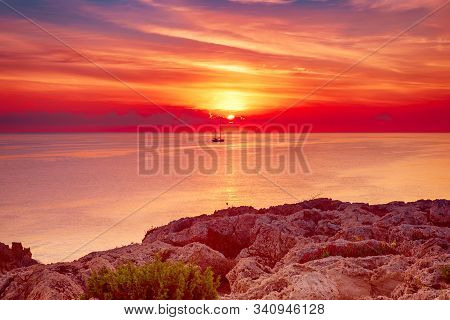 Beautiful Colorful Sunrise At The Sea With Dramatic Clouds, The Sailing Boat And Sun Shining