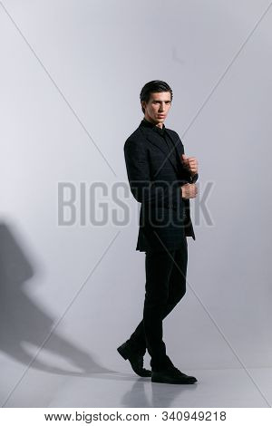 Full Length Portrait Of A Man In Suit, Poses With Attitudine, Over White Background. Touching His Bu