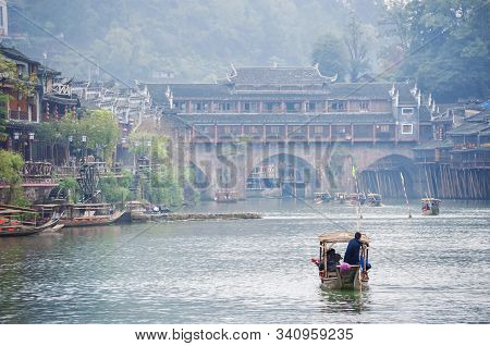A Tourist Boat Rows Along The Tuojiang Rover Towards Rainbow Bridge In The Ancient Watertown Of Feng
