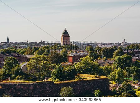 View Of Suomenlinna And Its Old Buildings And Lighthouse With Green Trees On A Summer Day With The H