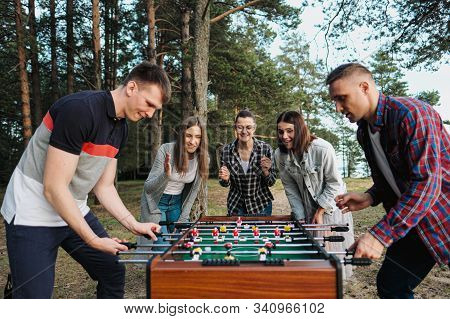 Friends Play Table Football Or Kicker Outdoors. Players And Fans Rejoice In The Victory.