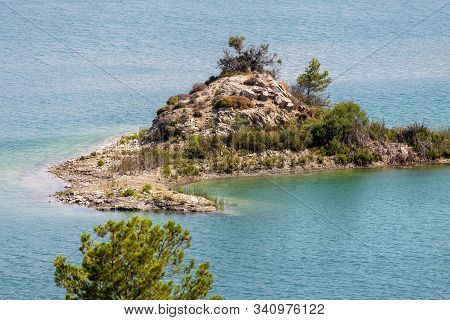 Small Island Of Rocks And With Green Trees In The Gadoura Water Reservoir On Rhodes Island, Greece O