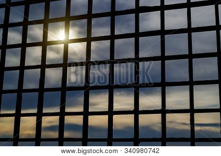 Look Through The Bars At The Sky. Pale Sunlight Breaking Through The Dark Clouds. To Be Imprisoned O