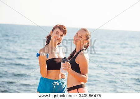 Fitness Girls With Shaker And Dumbbells On The Beach