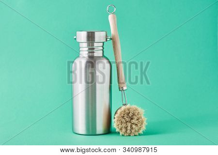 Zero Waste Concept. Eco Friendly Reusable Aluminun Bottle And Wooden Cleaning Brush On A Green Backg