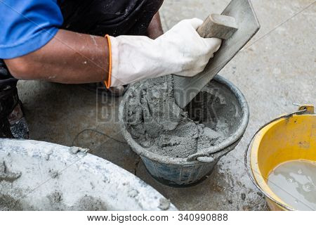 Close-up Of Worker's Hand Wixing Cement In Small Bucket Mixer.