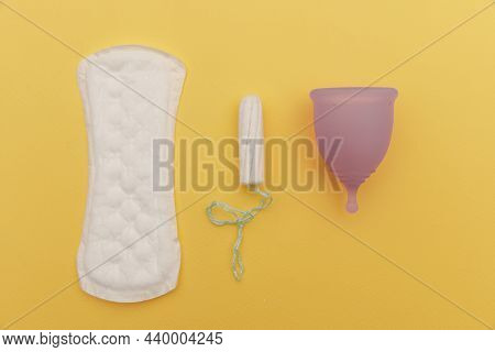 Pad, Menstrual Cup And Tampon On A Yelliw Background. Concept Of Critical Days And Hygiene