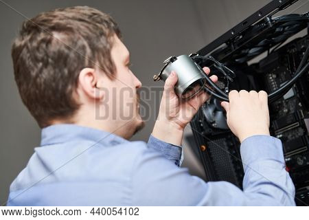 Computer assembling service. Serviceman installing liquid cooling system on processor