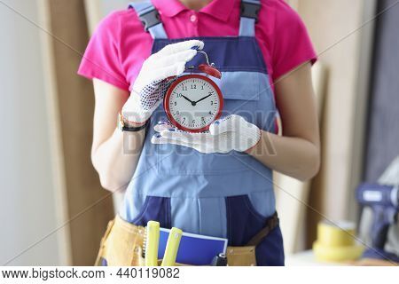 Close-up Of Woman Worker In Uniform Holding Red Clock Reminder To Finish Work On Time. Foreman At Co
