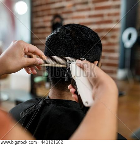 Hairdresser trimming hair of the customer at a barbershop