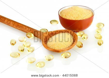 Gelatin in a bowl and wooden spoon on white background close-up