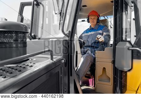 Happy Driver Man Of Industrial Dump Truck Sits In Cab And Works On Construction Building Site