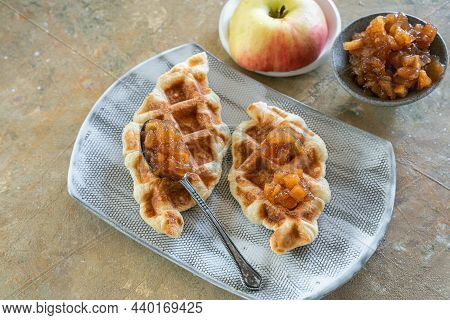 Two Waffles Of Croffle With Apple Jam Are On A Ceramic Plate.fresh Half Of An Apple And A Saucepan W