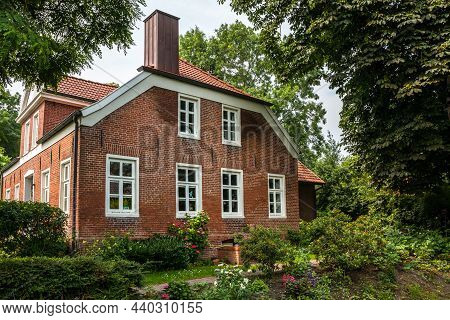 House Made Of Red Clincker Bricks Surrounded By Green Trees