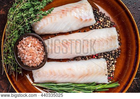 Raw Haddock Loin Fillet Fish On Rustic Plate With Thyme And Salt. Dark Background. Top View