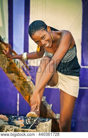 Young African woman with braids and short trousers fashion posing in an old grungy warehouse