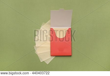 Package With Facial Oil Blotting Tissues On Green Background, Flat Lay. Mattifying Wipes