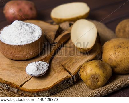 Potato Starch With Potatoes On A Dark Wooden Background.
