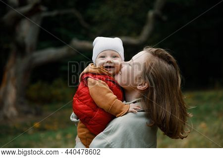 Mother With A Baby In Her Arms On A Walk. A Woman With A Child In Nature In The Park