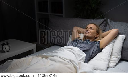 Pleasant Mature Woman In Pajamas Lying On Comfy Bed With Soft Linen And Enjoying Relaxation Time. Ca