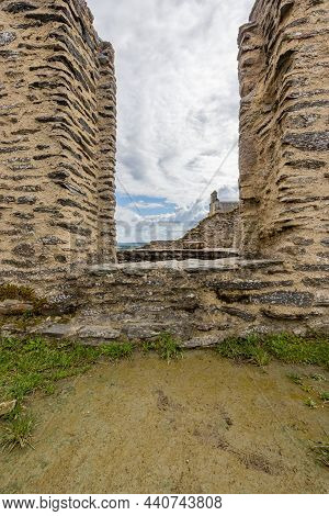 Opening Between Two Deteriorated Stone Walls Or Window With More Ruins And A Blue Sky With Abundant 