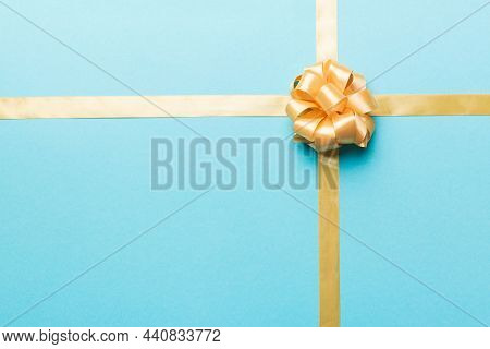 Top View Of Gold Ribbon Rolled And Yellowbow Isolated On Colored Background. Flat Lay With Copy Spac