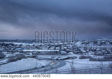 Hafnarfjordur, Iceland - November 24, 2021: A City Panorama On A Dark, Snowy Winter Day. Dark, Cloud