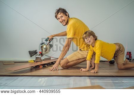 Father And Son Installing New Wooden Laminate Flooring On A Warm Film Floor. Infrared Floor Heating 
