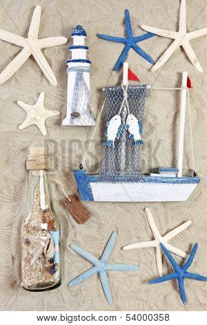Lighthouse, ship, bottle and sea stars on sand