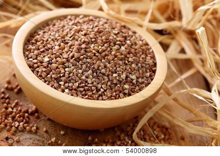 Dry buckwheat groats on wooden bowl