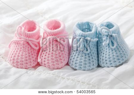 Blue and pink baby booties on white background