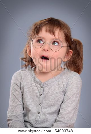 Fanny little girl with glasses on grey background