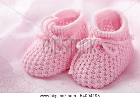 Pink baby booties on pink background