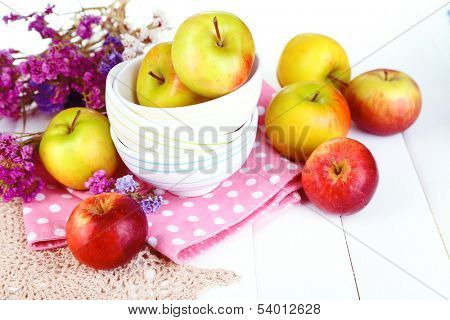 Juicy apples on plate on white wooden table