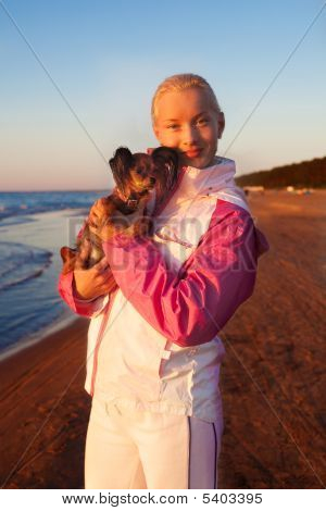 Ung smuk kvinde med hendes hund på en strand