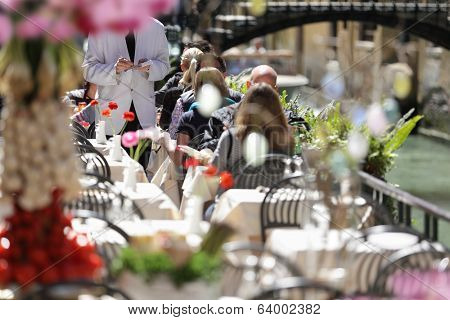 Outdoor cafe scene with waiter in white jacket taking order