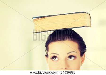 Attractive young student woman with book on head