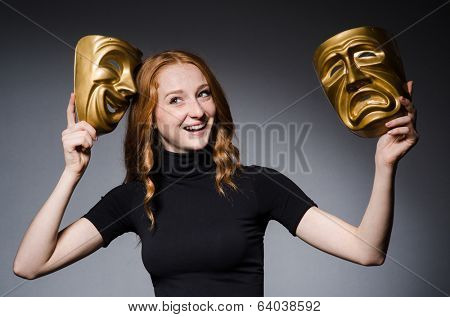 Redhead woman iwith masks in hypocrisy consept against grey background