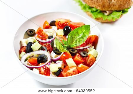Light Greek Salad With Fresh Vegetables And Burger In The Background. On White.