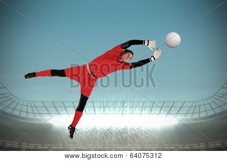 Fit goal keeper jumping up against large football stadium with spotlights