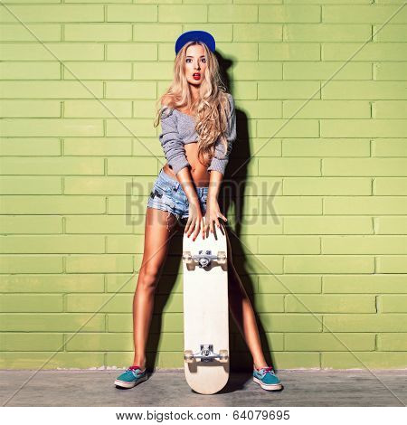 Sexy Suntan Girl In Short Jeans Shorts Against Green Brick Wall