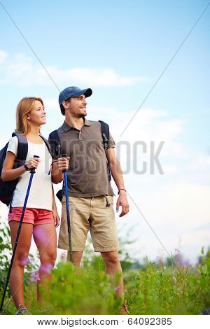 Couple of smiling trippers standing in the countryside at summer