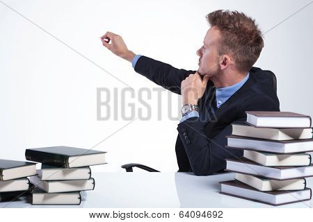 young business man sitting at the office and writing something with chalk on an imaginary screen behind him. on a light studio background
